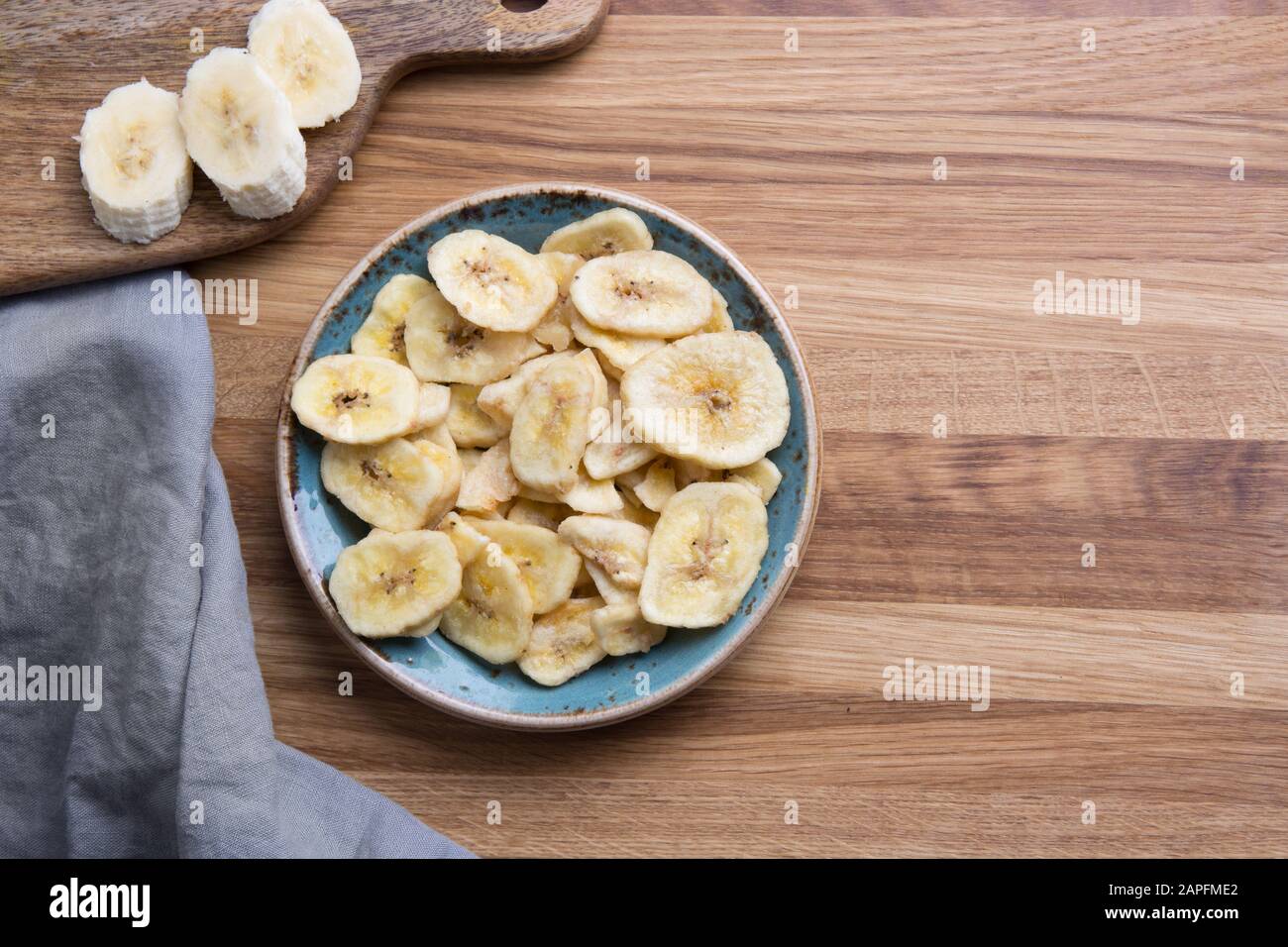 Chips de bananes déshydratées, fraîches et séchées sur la planche à découper. Vue de dessus. Banque D'Images