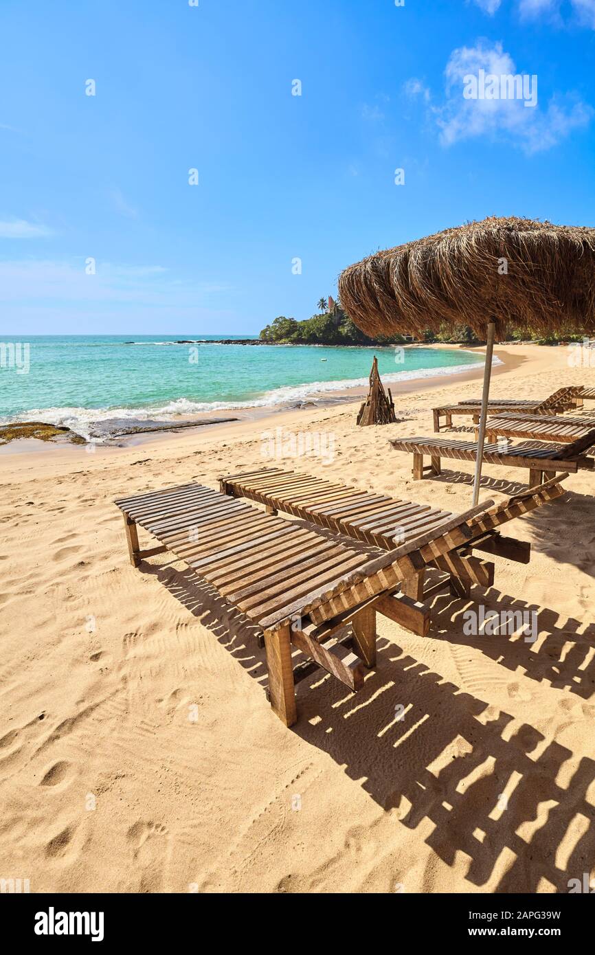Chaises longues en bois sur une plage tropicale, concept de vacances d'été. Banque D'Images