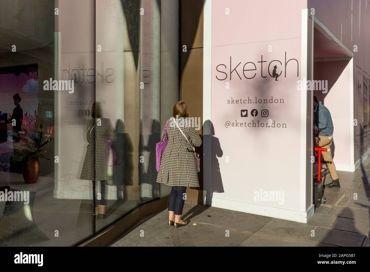 Une jeune femme tient une conversation téléphonique privée dans un coin ensoleillé à côté de 'sketch', une galerie de gastro sur conduit Street, le 20 janvier 2020, à Londres, en Angleterre. Banque D'Images