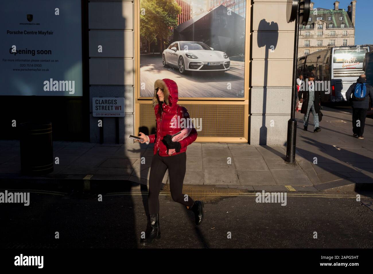 Une dame porte son téléphone tout en marchant devant une annonce de luxe Porsche où une nouvelle concession est due à l'ouverture à l'angle de Clarges Street, et Piccadilly,  , le 20 janvier 2020, à Londres, en Angleterre. Banque D'Images