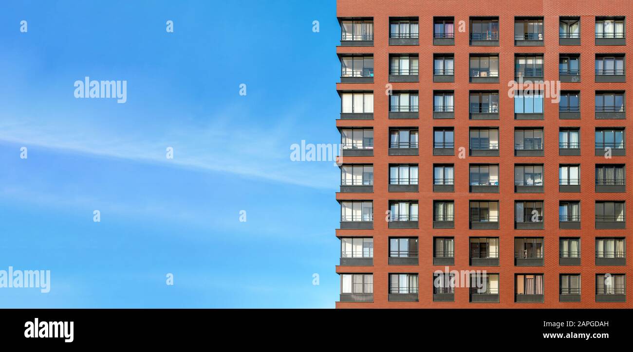 La façade moderne en brique d'un bâtiment en hauteur contre le ciel bleu Banque D'Images