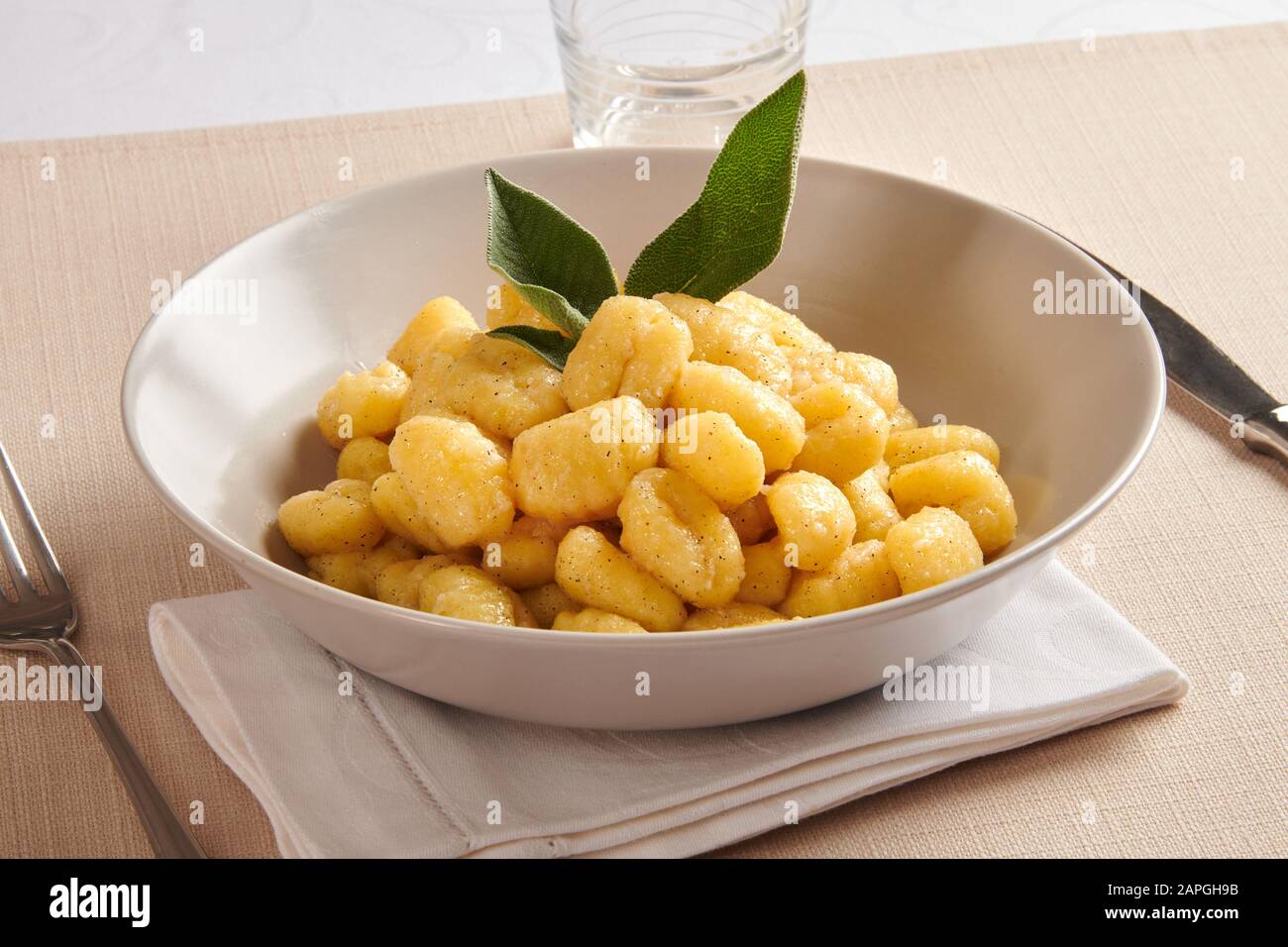 Plat régional traditionnel de pâtes gnocchi au beurre et au salvia de la région de Vénétie en Italie servi à table sur une serviette pliée Banque D'Images
