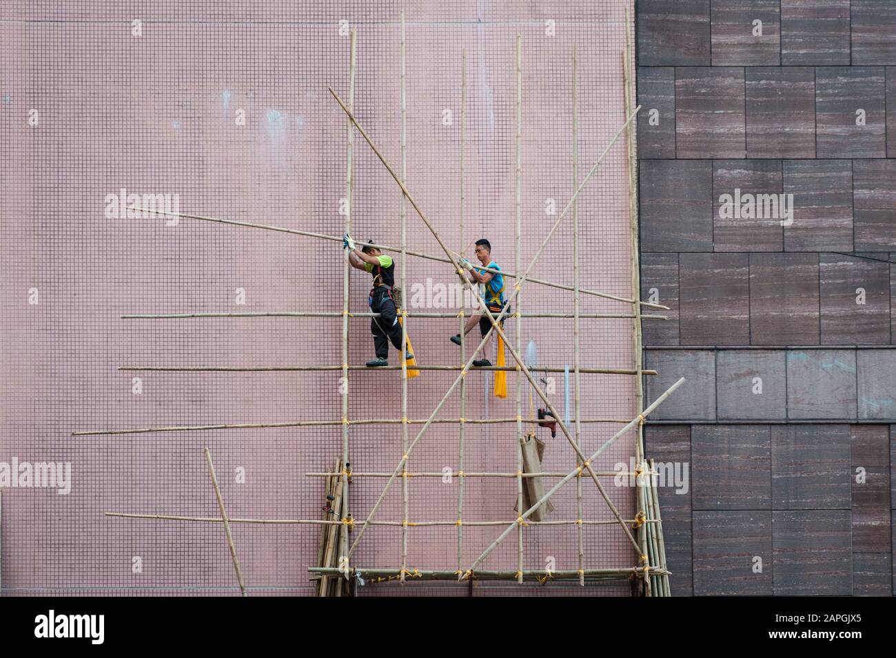 Hong Kong, novembre 2019: Travailleurs sur le chantier de construction de l'échafaudage en bambou sur la façade de maison à Hong Kong Banque D'Images