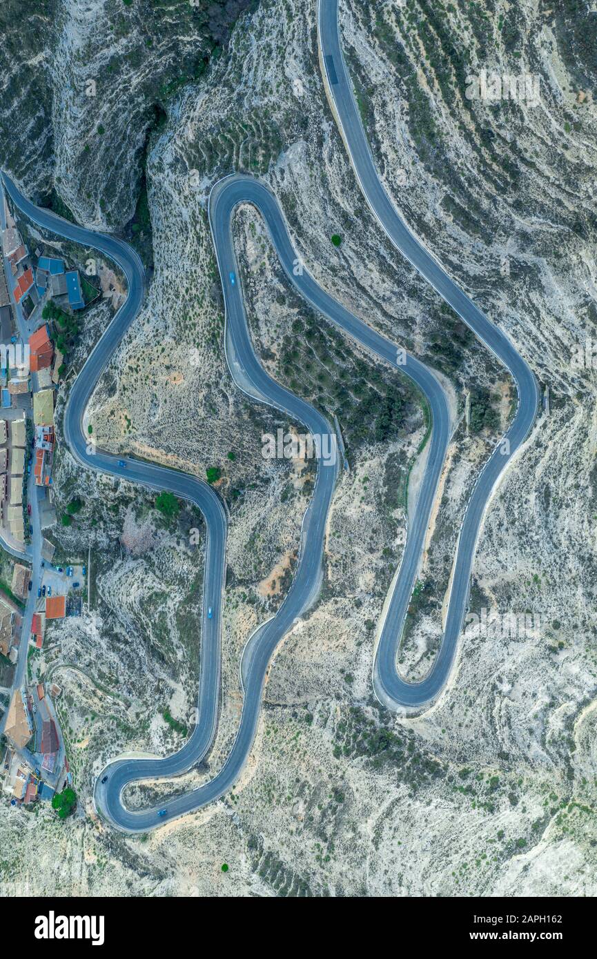 Vue panoramique aérienne de haut en bas d'une longue route en serpentine courrant en haut de la colline depuis le fond de la rivière du Jucar avec des dizaines de virages serrés Banque D'Images