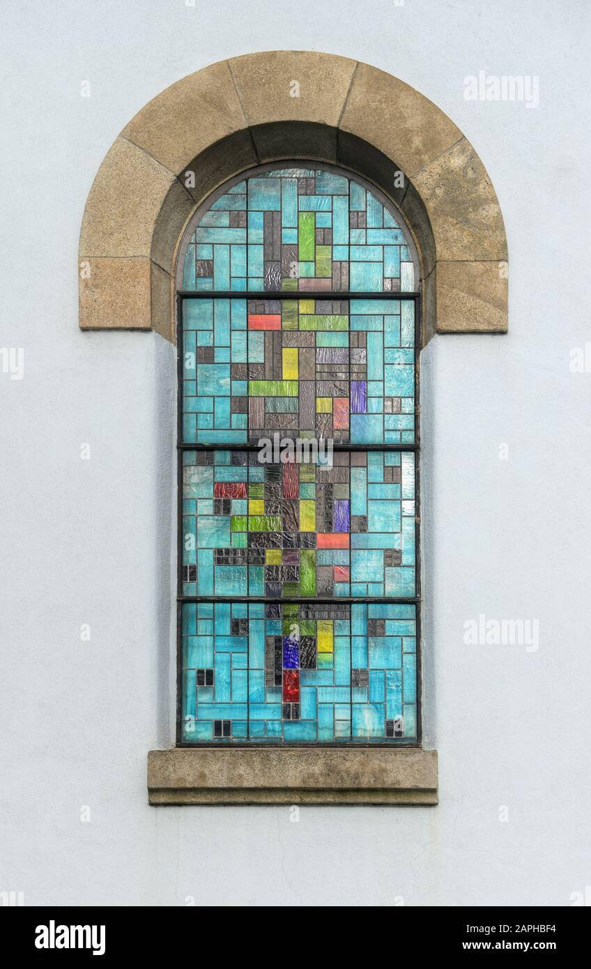 Fenêtre colorée en vitrail d'une église contraste avec le blanc pur du mur Banque D'Images