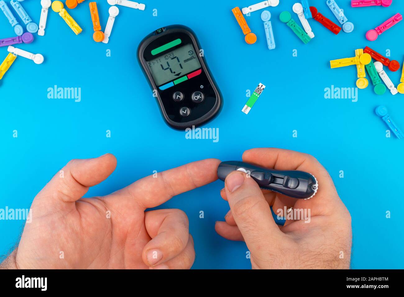 Test de diabète. Mains de l'homme vérifiant le taux de sucre dans le sang par le glucomètre sur fond bleu. Dispositif de mesure des taux de sucre dans le sang. Bandelettes de test, pilules Banque D'Images