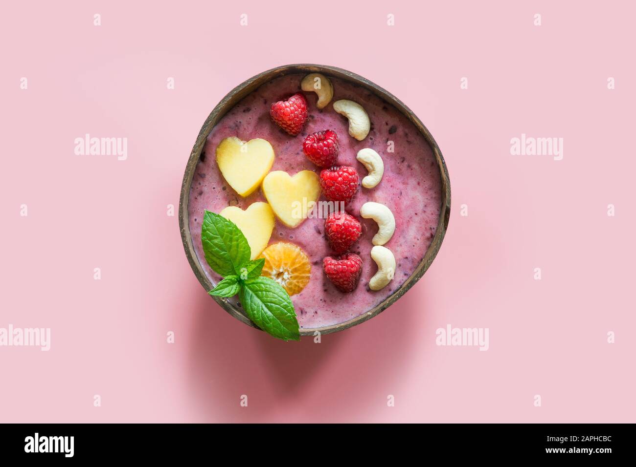 Petit-déjeuner sain et bananes smoothie bleuet décoré de fruits dans un bol de noix de coco sur fond rose. Vue de dessus. Manger végétarien, propre fo Banque D'Images
