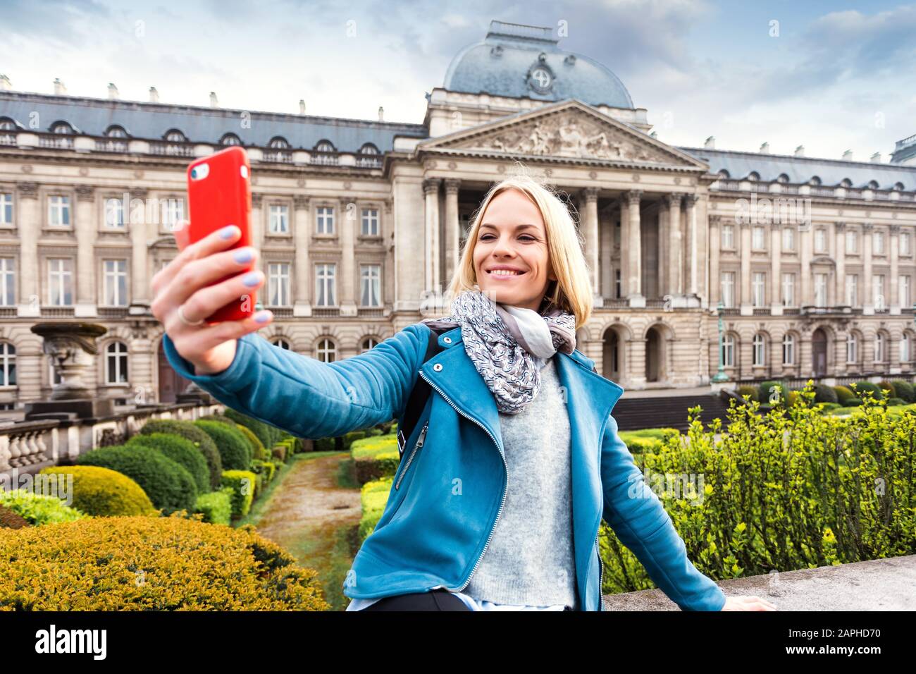 Une jeune femme se tient devant le palais royal de Bruxelles et prend un selfie sur son téléphone, la Belgique Banque D'Images