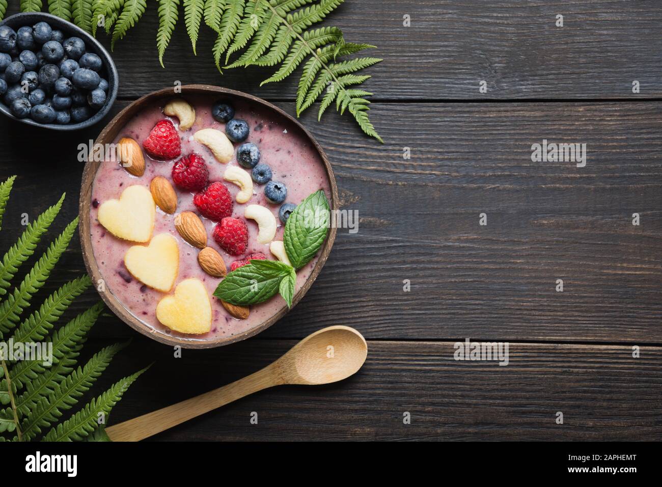 Petit déjeuner tropical sain et bananes smoothie bleuet décoré de fruits dans un bol de noix de coco sur planche de bois. Vue de dessus. Manger propre, vegetar Banque D'Images