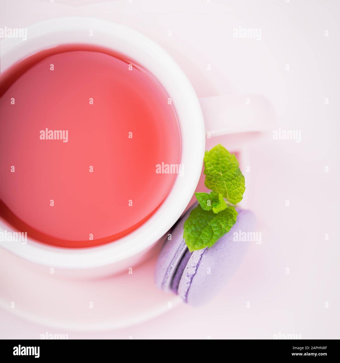 Thé aux fruits, macaron blackberry ou macaron avec feuille de menthe sur fond rose pâle, espace de copie Banque D'Images