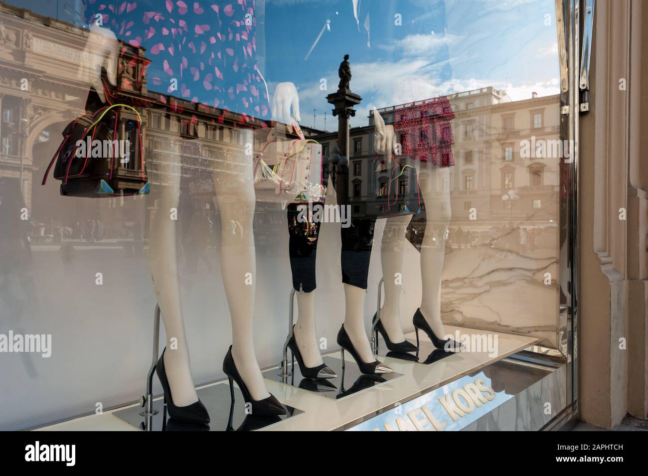Florence, Italie - 2020, Jan 19: Mannequins avec sacs et talons hauts noirs dans les vitrines de mode Michel Kors. Paysage urbain reflété dans la fenêtre. Banque D'Images
