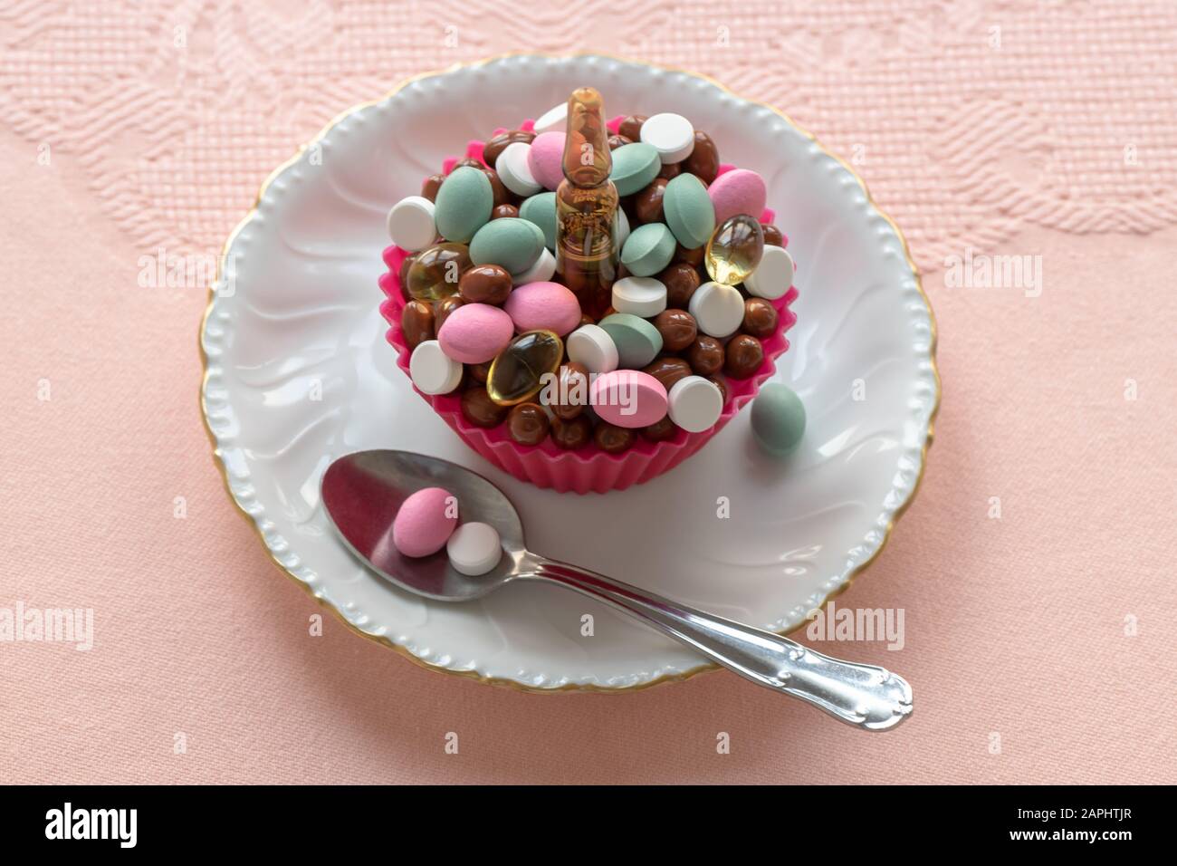 Cupcake fait de pilules sur une plaque blanche et de nappe rose. Prêt à manger. Consommation, utilisation et abus de produits pharmaceutiques. Banque D'Images