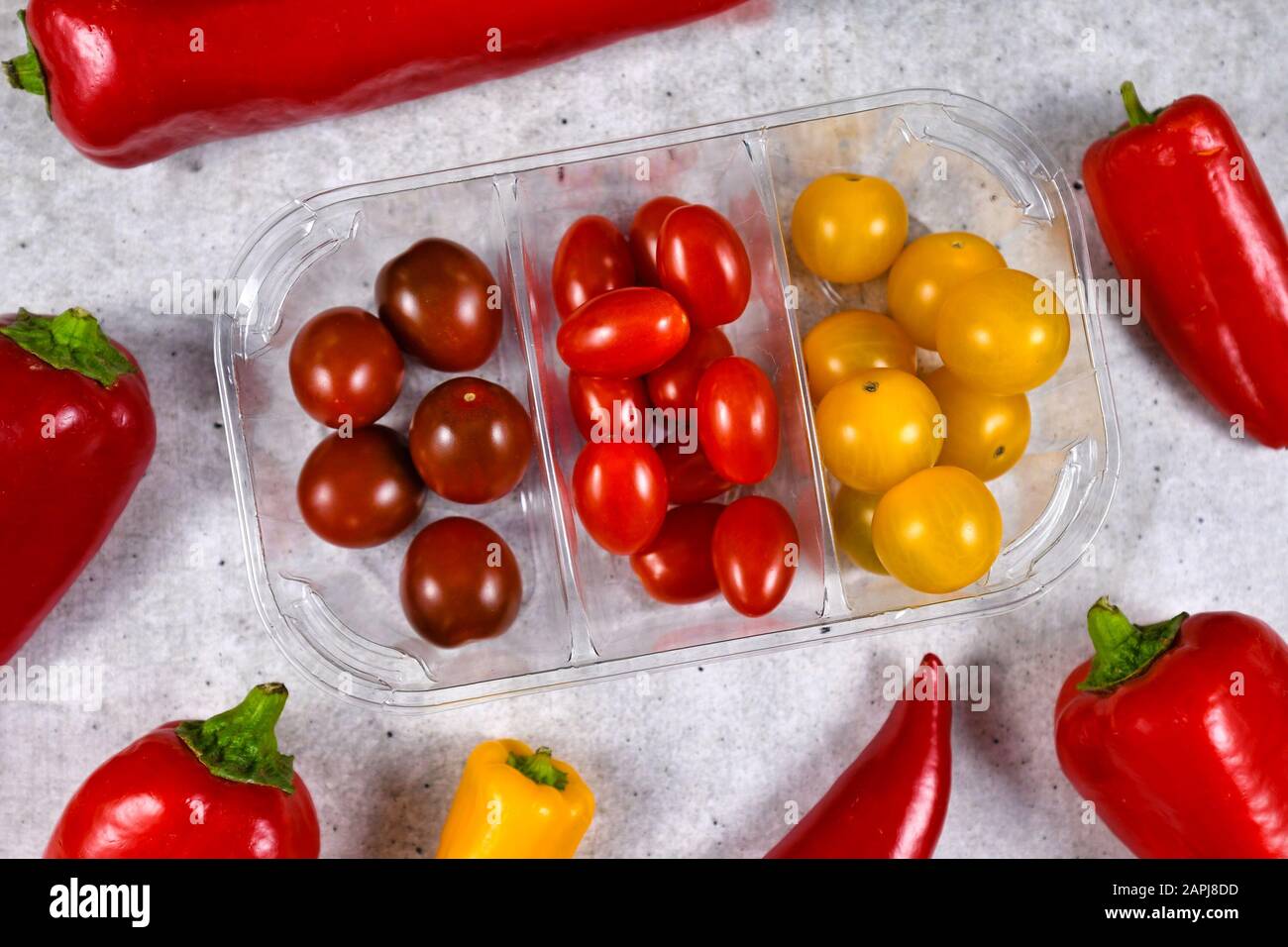 Mélanger différents types de petits légumes rouges, rouges foncé et jaunes de tomates cerises dans un récipient en plastique Banque D'Images