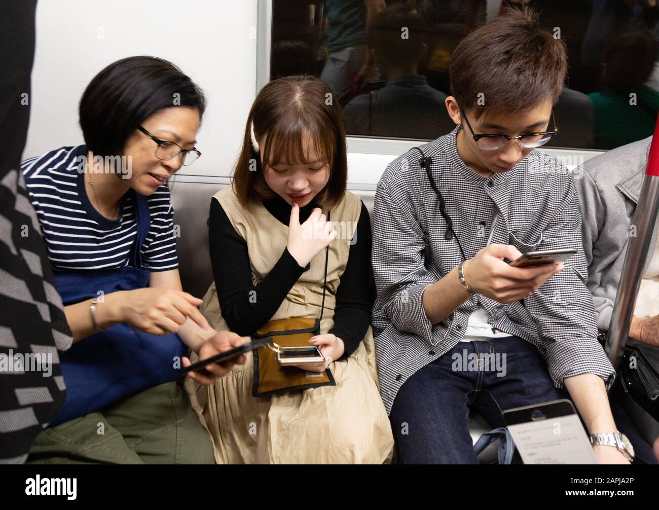 Hong Kong MTR - les gens en transport sur le train de transport en commun de Hong Kong utilisant leurs téléphones mobiles, Hong Kong Asia Banque D'Images