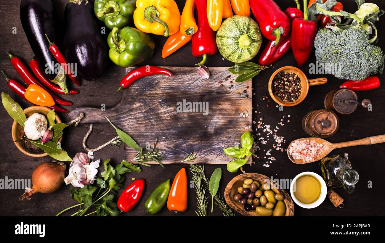 couleurs et saveurs de différents types de légumes et ingrédients sur la table et le tableau de découpe du bois brut Banque D'Images