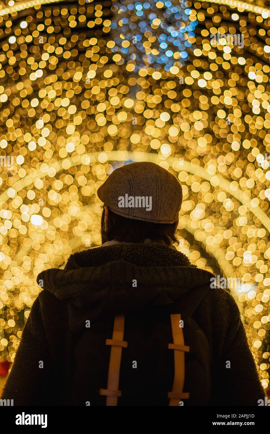 Homme vu de derrière avec des lumières de noël en arrière-plan Banque D'Images