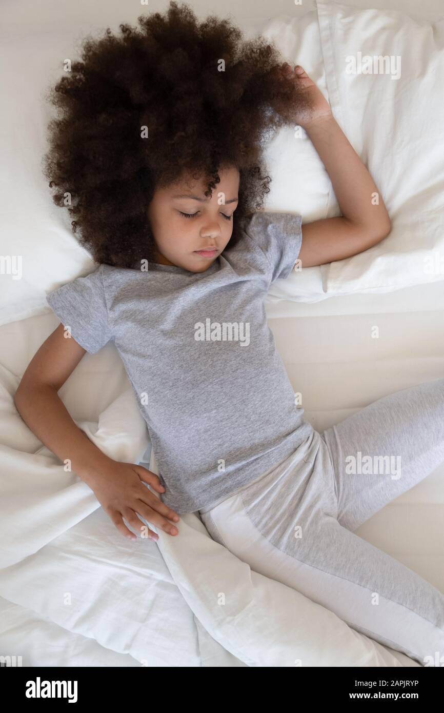 Vue verticale vue rapprochée fille africaine dormant dans le lit à l'intérieur Banque D'Images