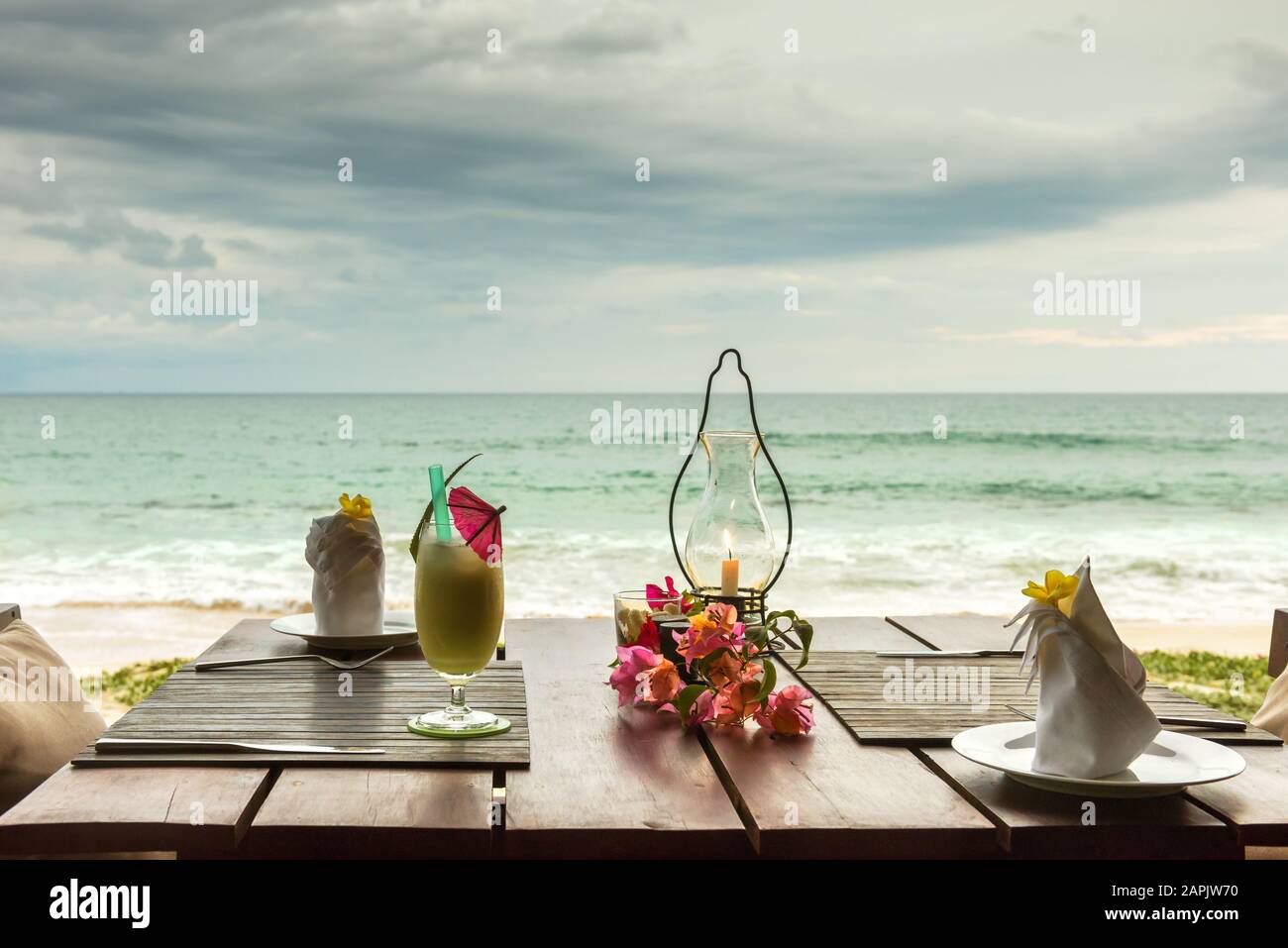 Table pour le dîner avec cocktail et fleurs sur une plage tropicale Banque D'Images