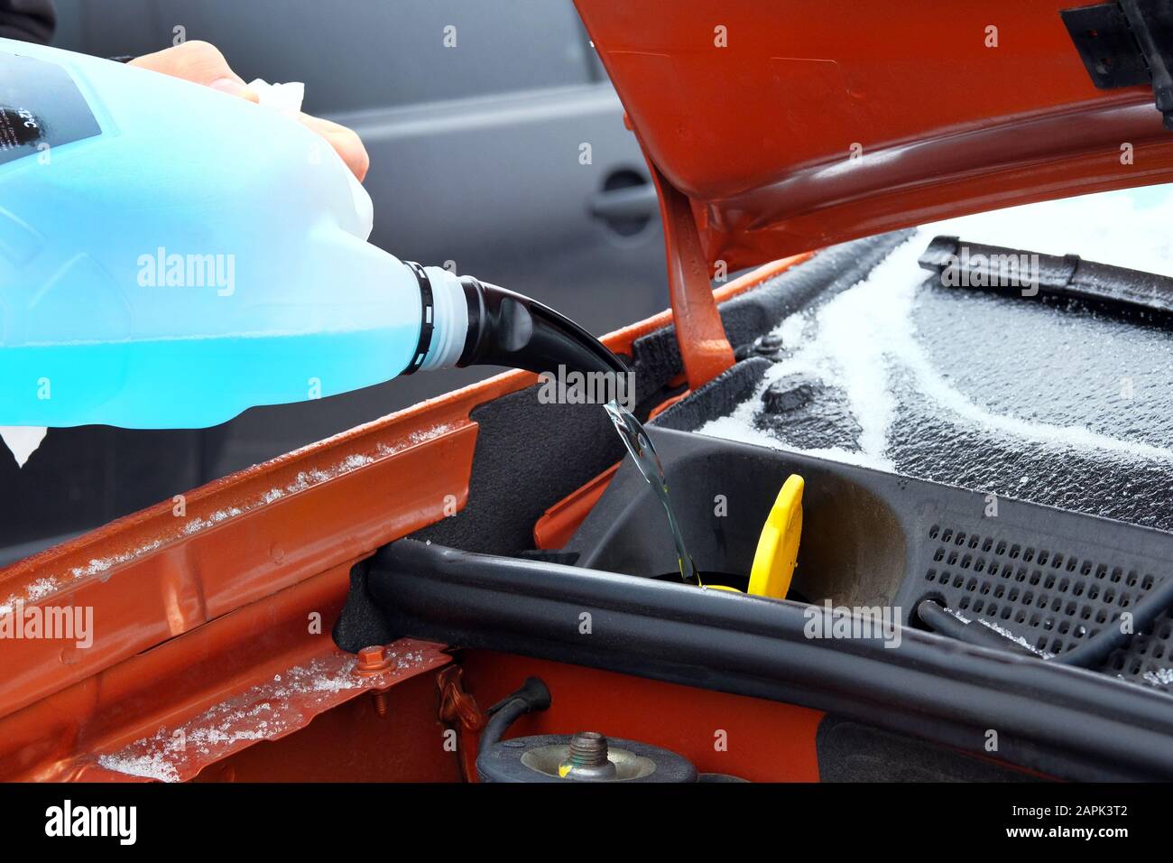Concept d'entretien automobile. Remplissage du liquide de lave-glace bleu sur la voiture en hiver. Gros plan. Banque D'Images