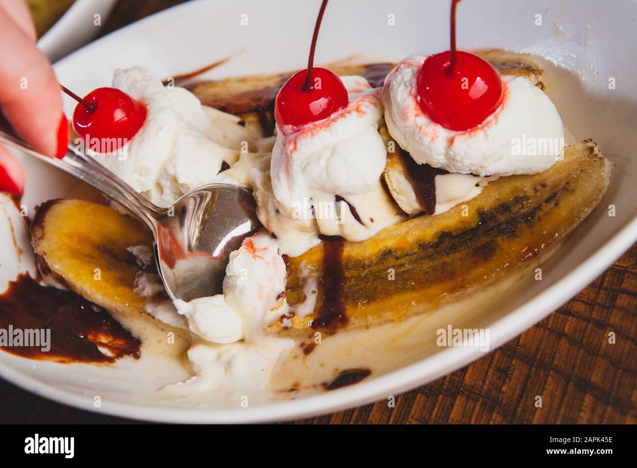 La banane est surmontée de cerises et de desserts au pudding, assis sur une table en bois. Banque D'Images