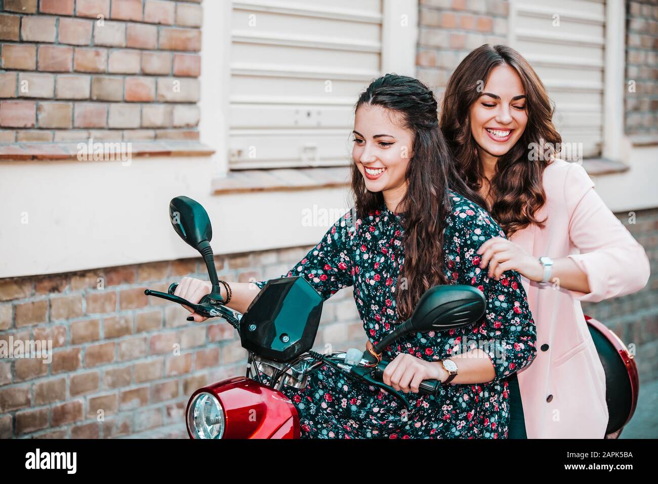Amuse-toi bien ensemble. Deux joyeuses femmes amis à moto ensemble à  travers la rue de la ville Photo Stock - Alamy