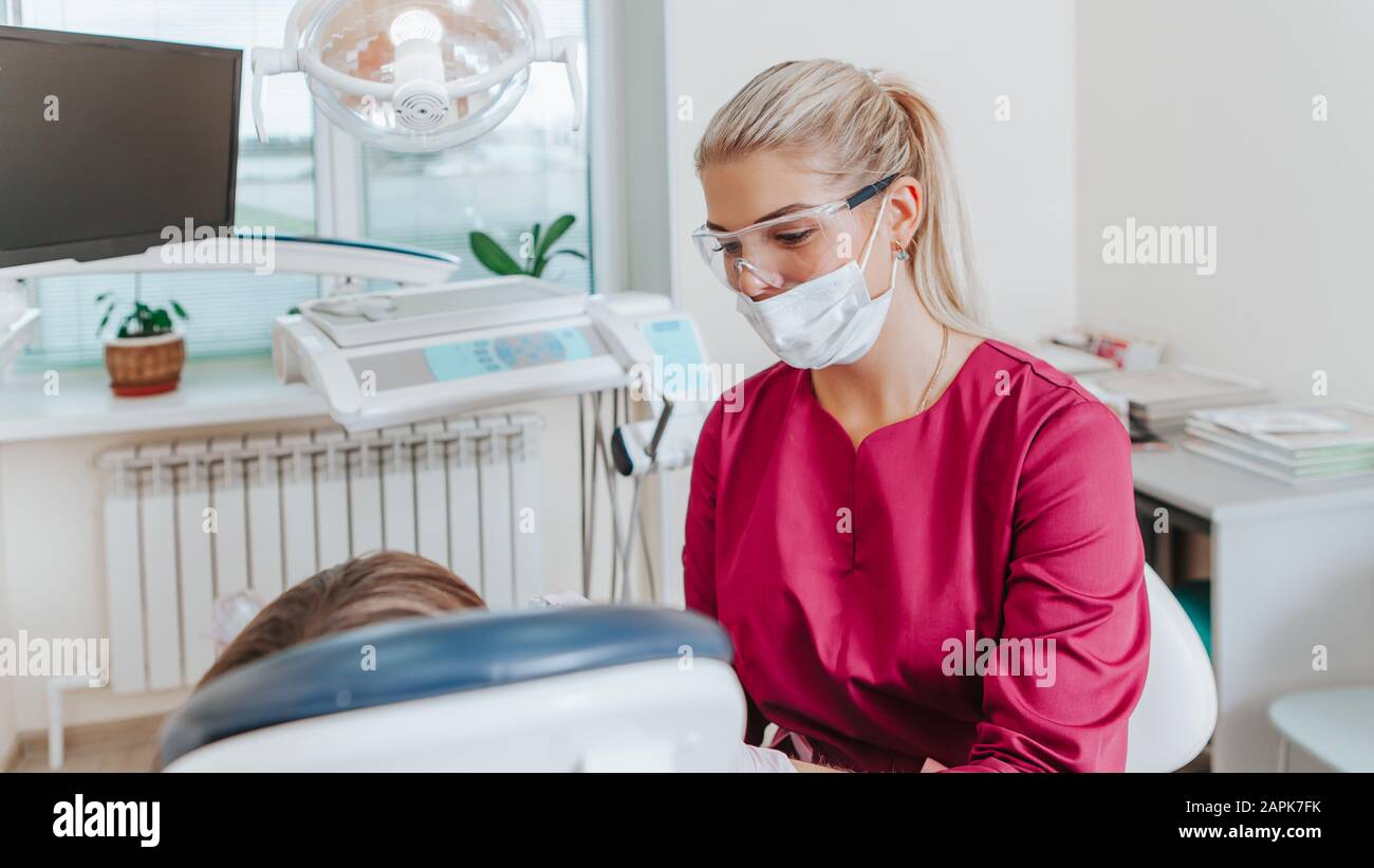 Une dentiste de bureau dentaire traite les dents avec un patient enfant. Banque D'Images