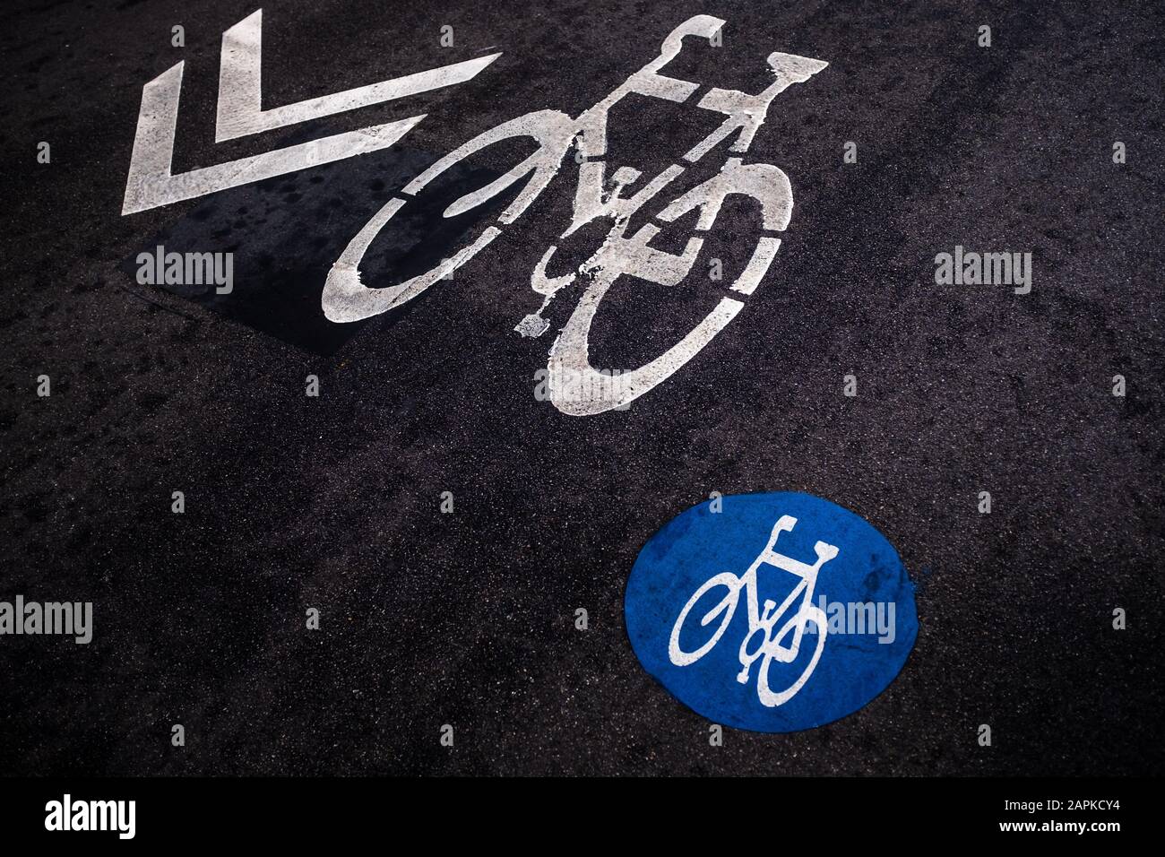 Marquage de la trajectoire du cycle sur un fond noir d'asphalte vu sous un angle élevé. Deux symboles de vélo et une flèche de direction différents, des marquages routiers. Banque D'Images