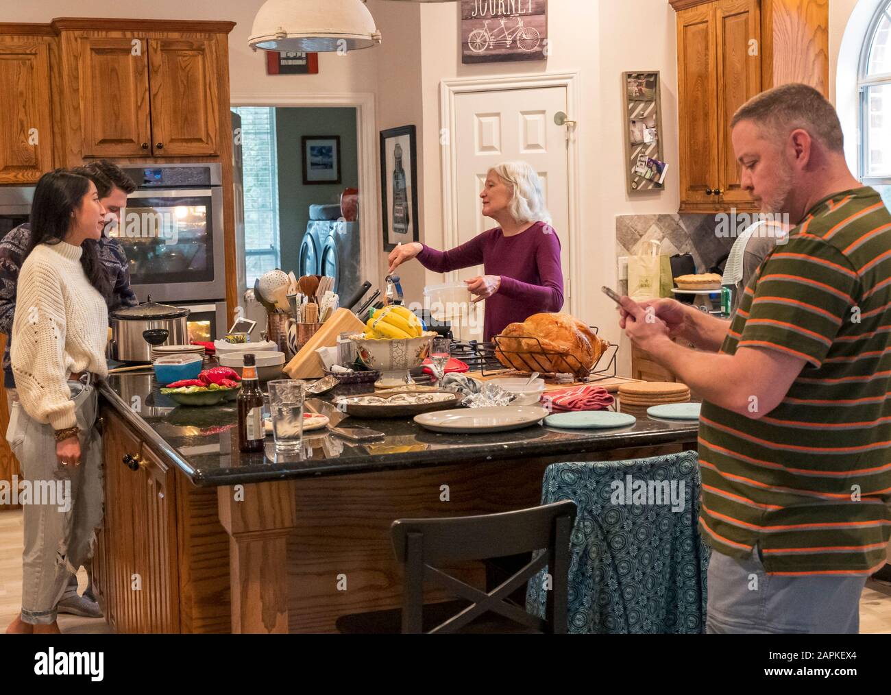 La famille s'est rassemblée autour de l'île du centre de cuisine pour un dîner de Thanksgiving de style buffet Banque D'Images