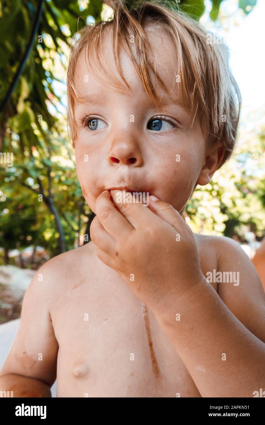 Un petit garçon mangeant une baie Banque D'Images