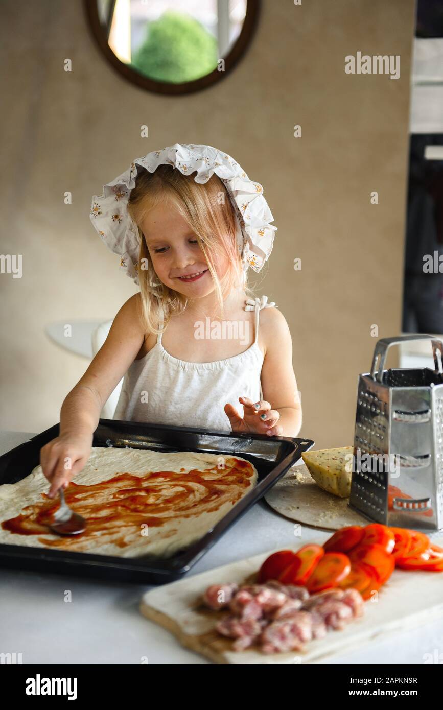 Une petite fille cuisant de la pizza dans la cuisine Banque D'Images