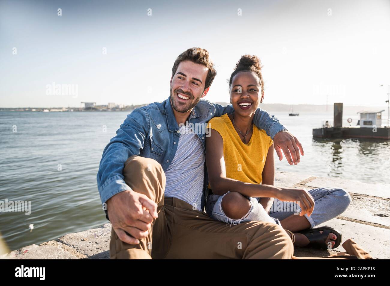 Happy young couple sitting on pier au Waterfront, Lisbonne, Portugal Banque D'Images
