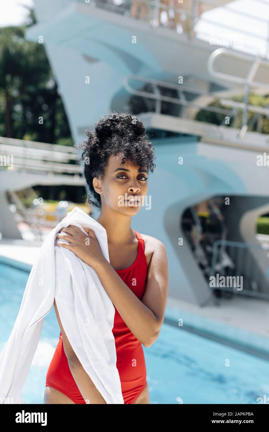 Portrait de la jeune femme dans une combinaison de bain rouge qui se trouve devant une piscine Banque D'Images