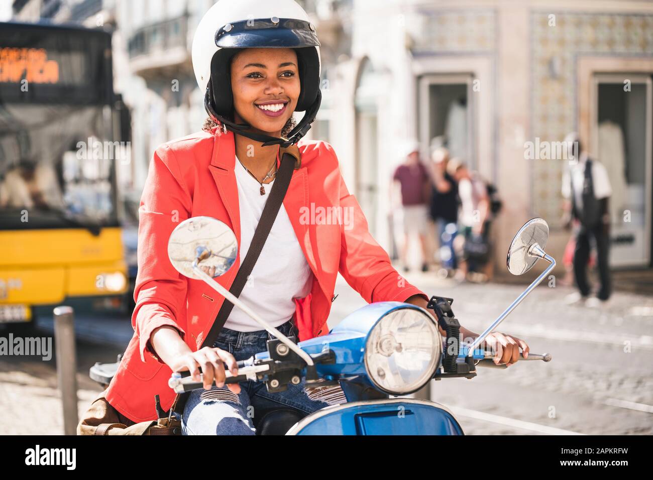 Jeune femme souriante à moteur en scooter dans la ville, Lisbonne, Portugal Banque D'Images