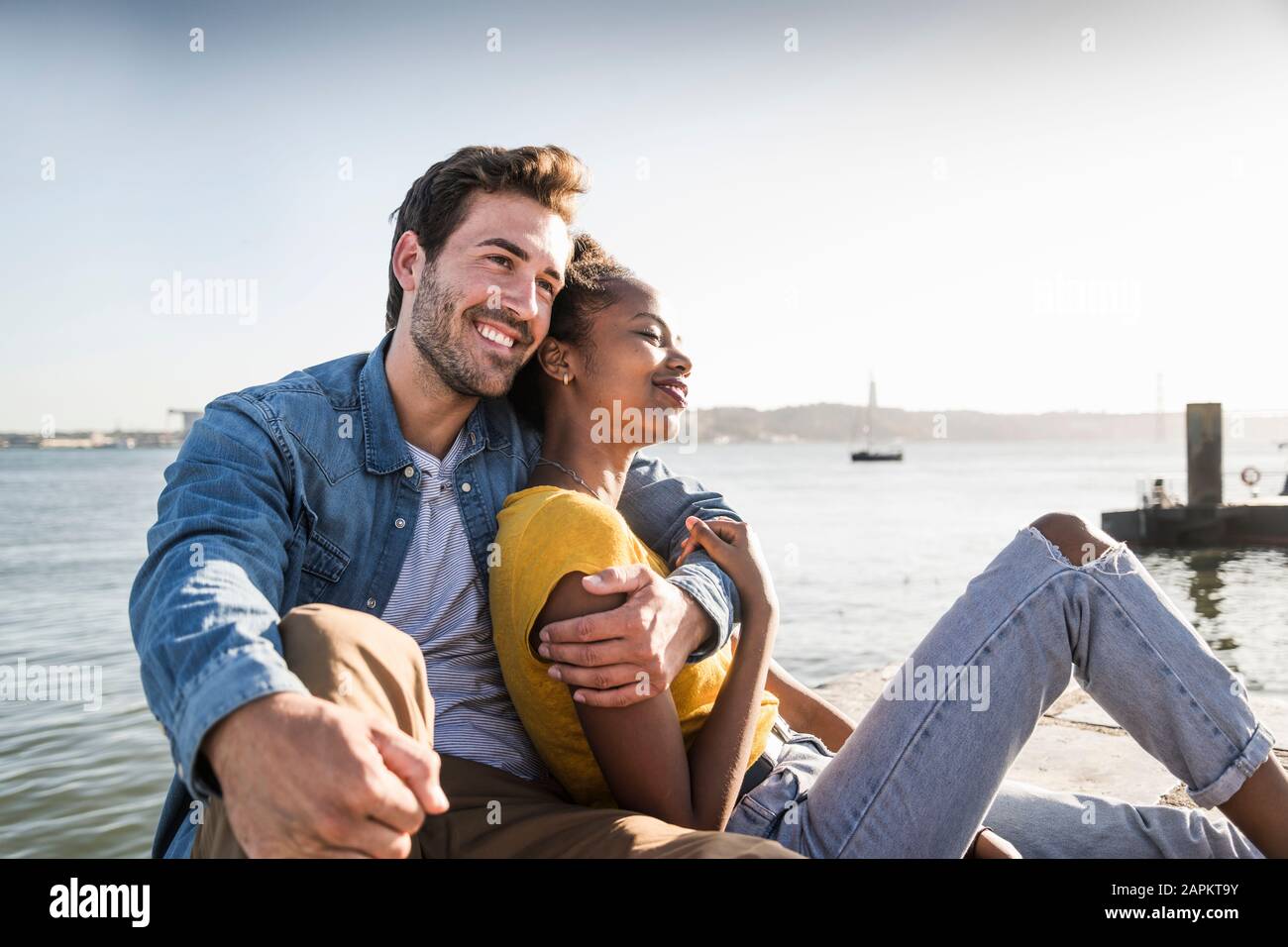 Happy young couple sitting on pier au Waterfront, Lisbonne, Portugal Banque D'Images