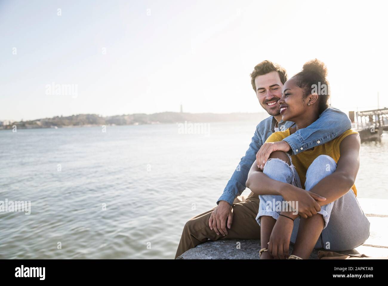 Happy young couple sitting on pier au Waterfront, Lisbonne, Portugal Banque D'Images