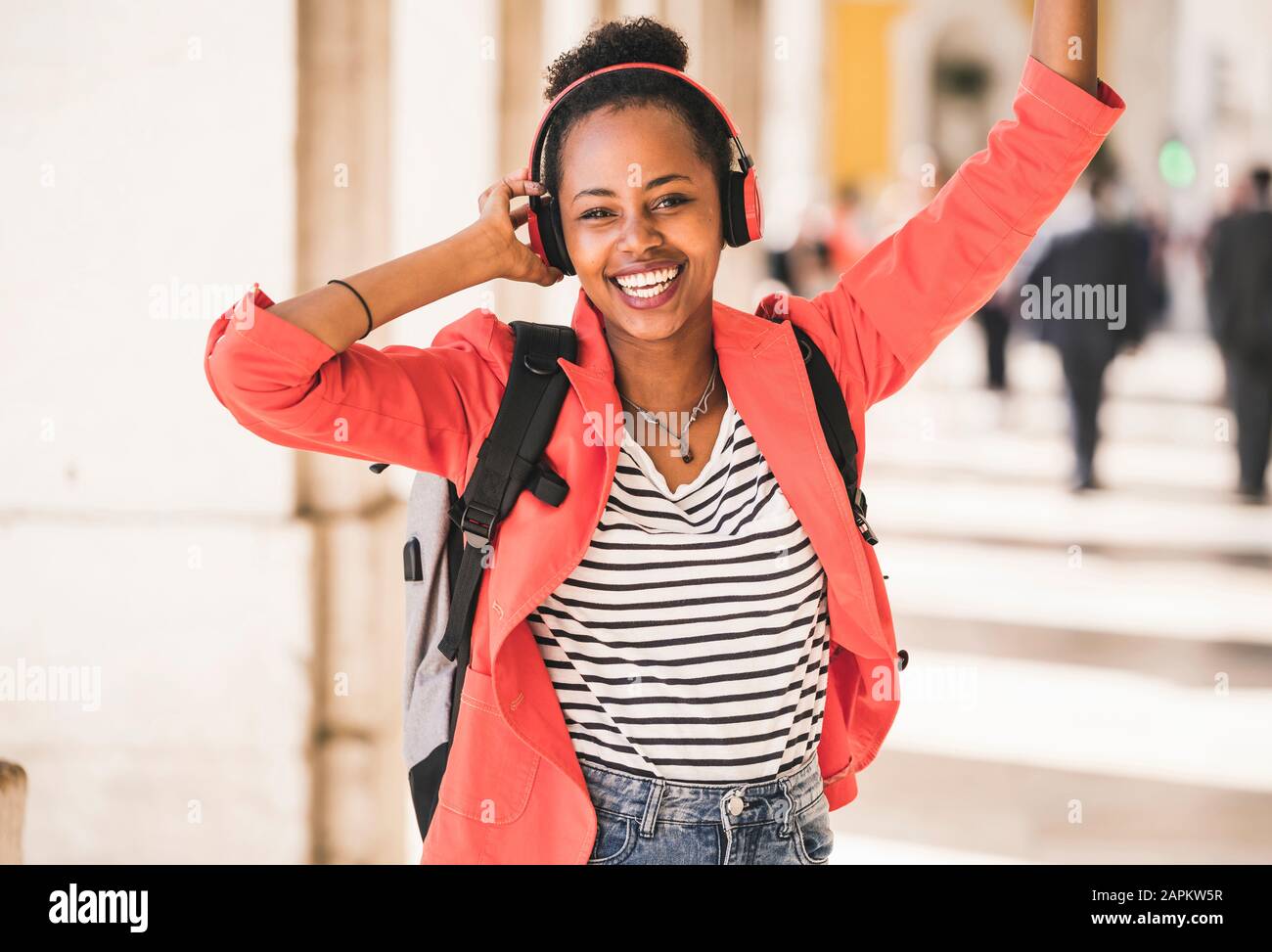 Portrait d'une jeune femme heureuse avec écouteurs écoutant de la musique dans la ville, Lisbonne, Portugal Banque D'Images