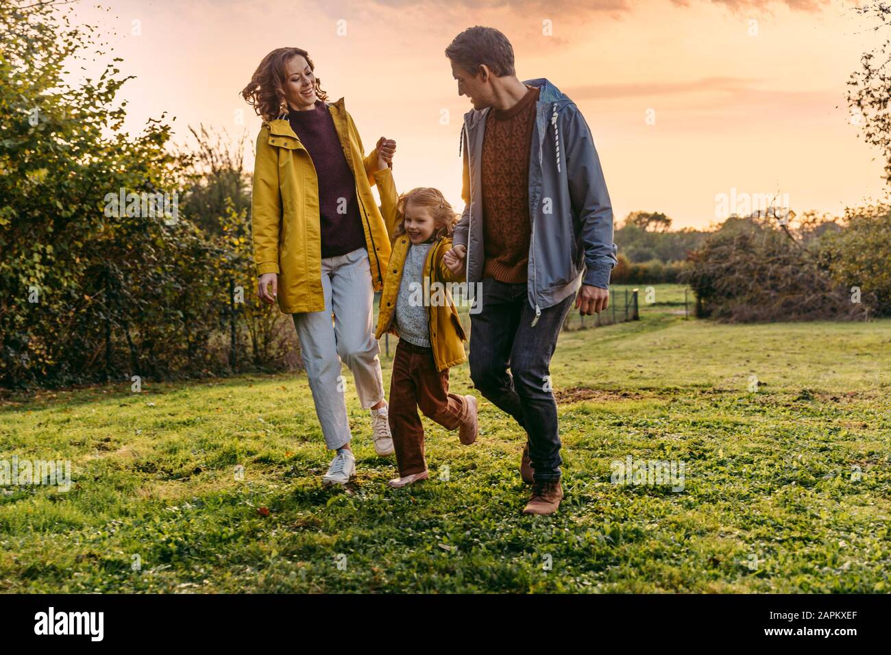 Parents avec fille marchant sur un pré en automne Banque D'Images