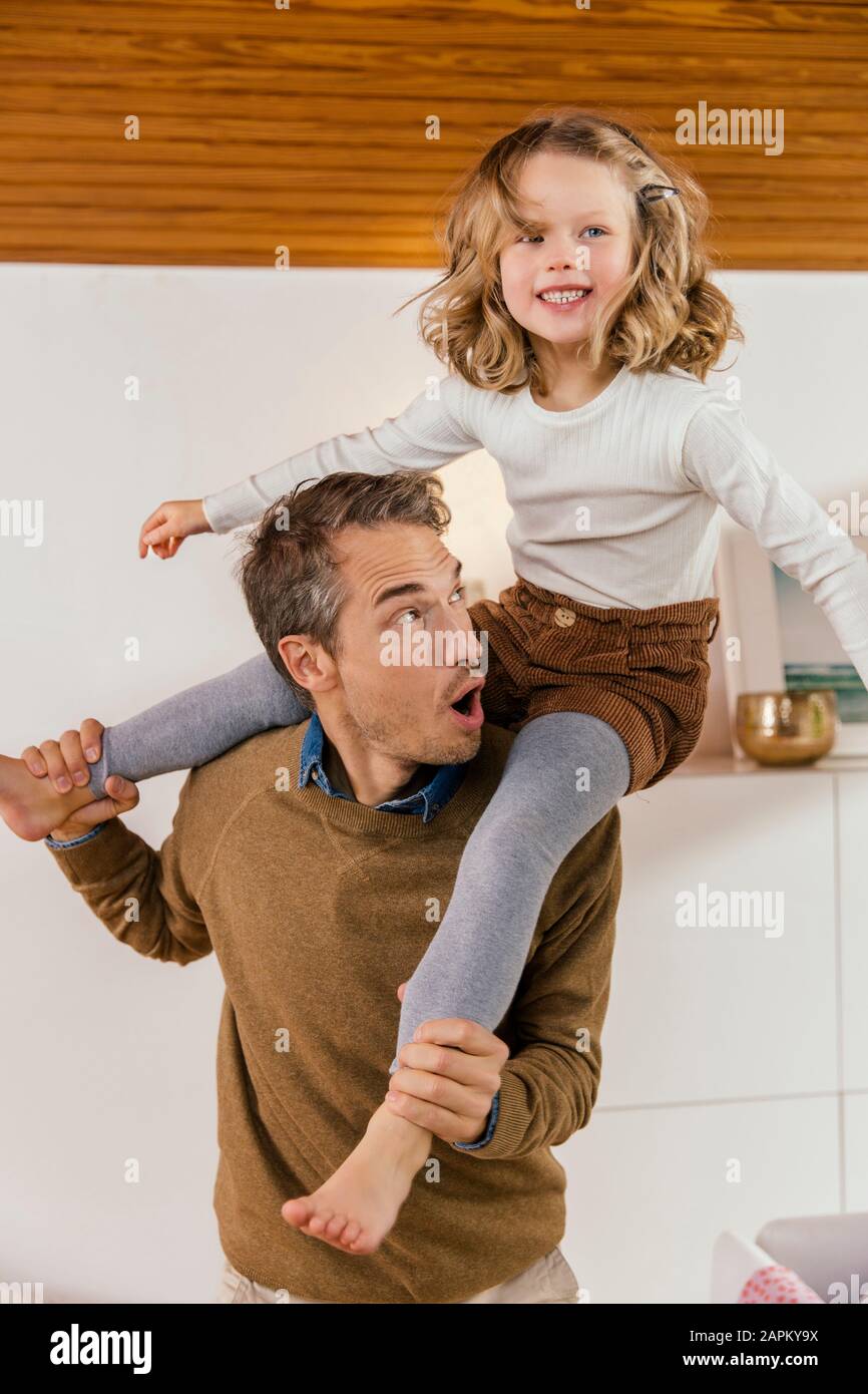 Joyeux père portant sa fille sur les épaules à la maison Banque D'Images