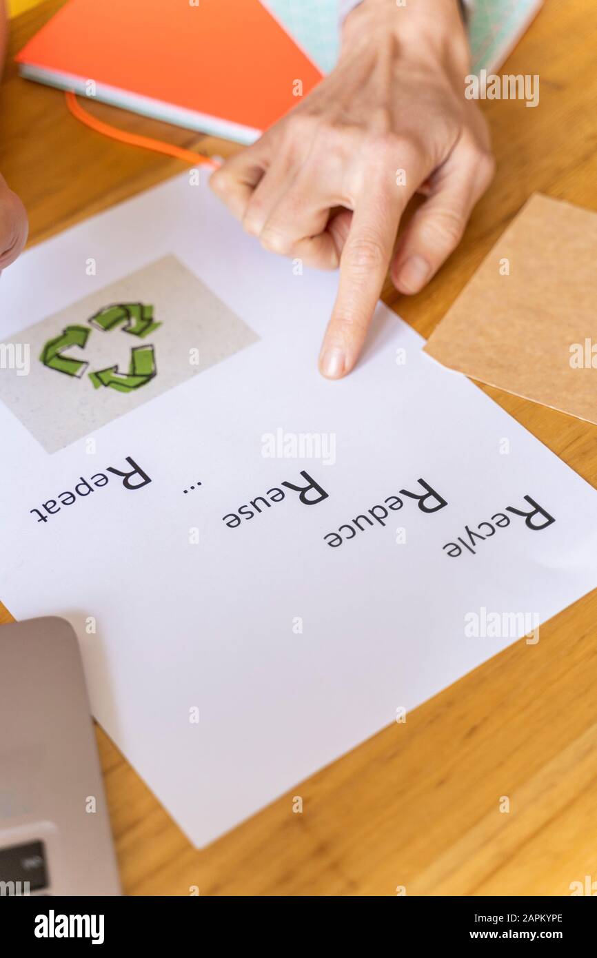 Femme d'affaires pointant sur du papier avec symbole de recyclage au bureau Banque D'Images