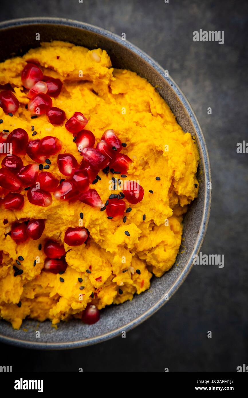 Bol de houmous de citrouille avec graines de sésame noir et de grenade Banque D'Images