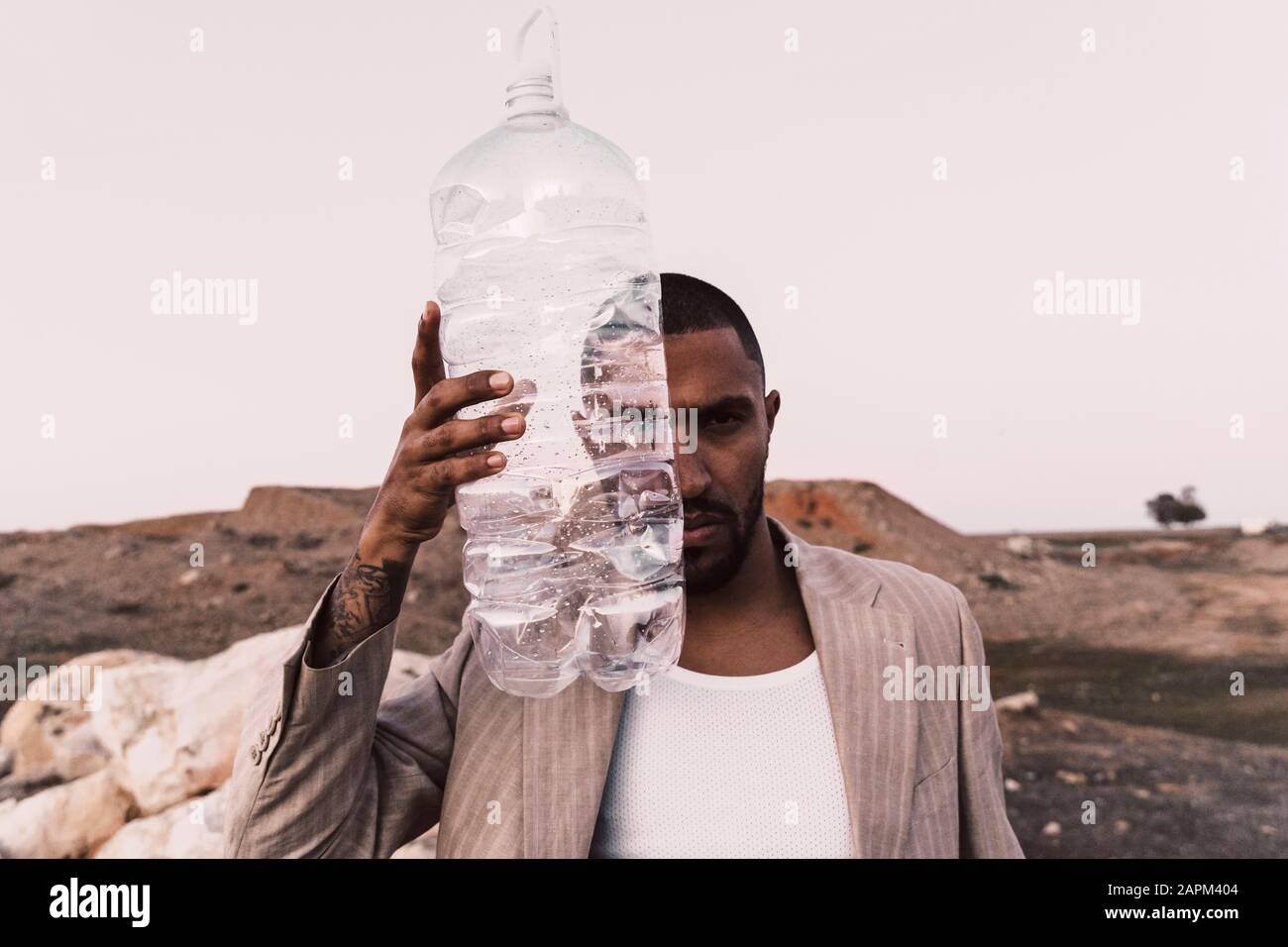 Portrait de jeune homme sérieux tenant une bouteille en plastique vide Banque D'Images