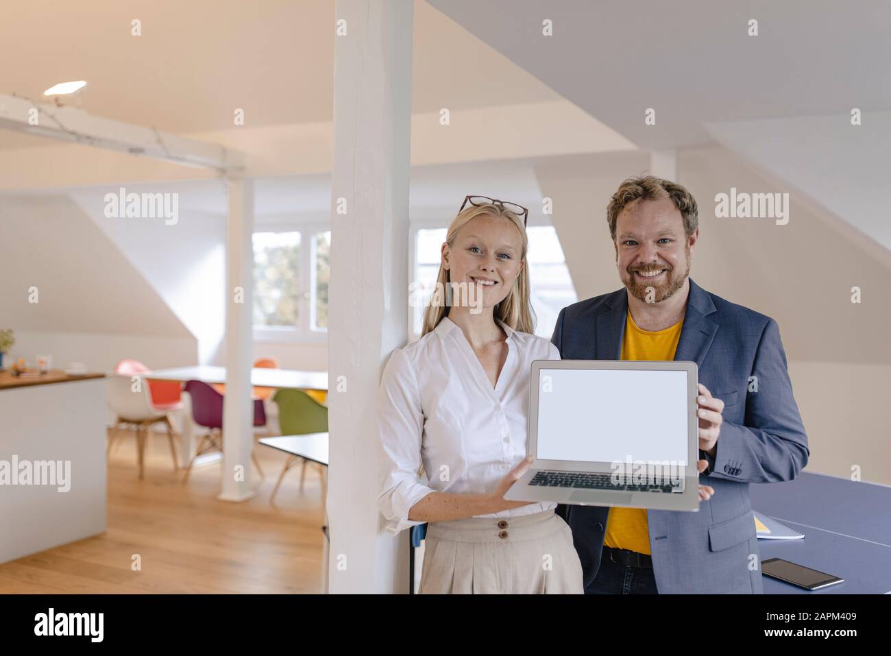 Portrait d'un homme d'affaires confiant et d'une femme d'affaires au bureau présentant un ordinateur portable Banque D'Images