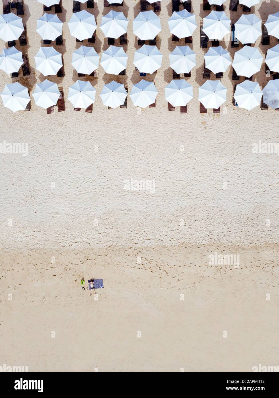 Indonésie, Bali, vue aérienne de l'homme qui bronzer devant des rangées de parasols sur la plage de sable de Nusa Dua Banque D'Images