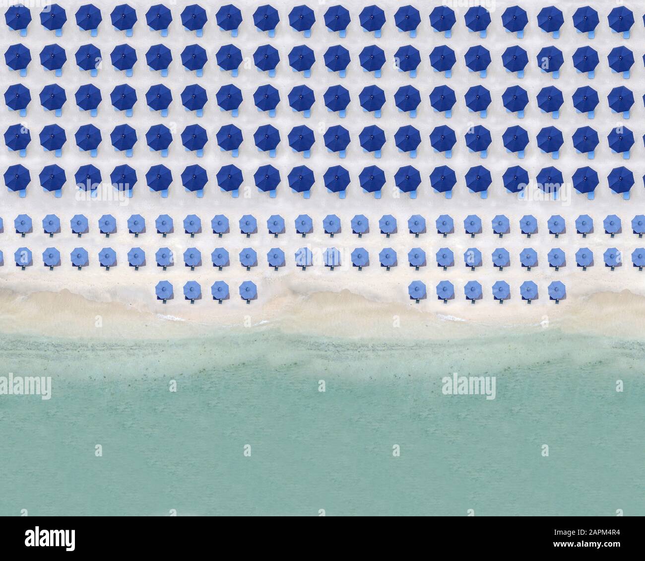Vue aérienne sur des rangées de parasols bleus se tenant le long de la plage de sable côtière Banque D'Images