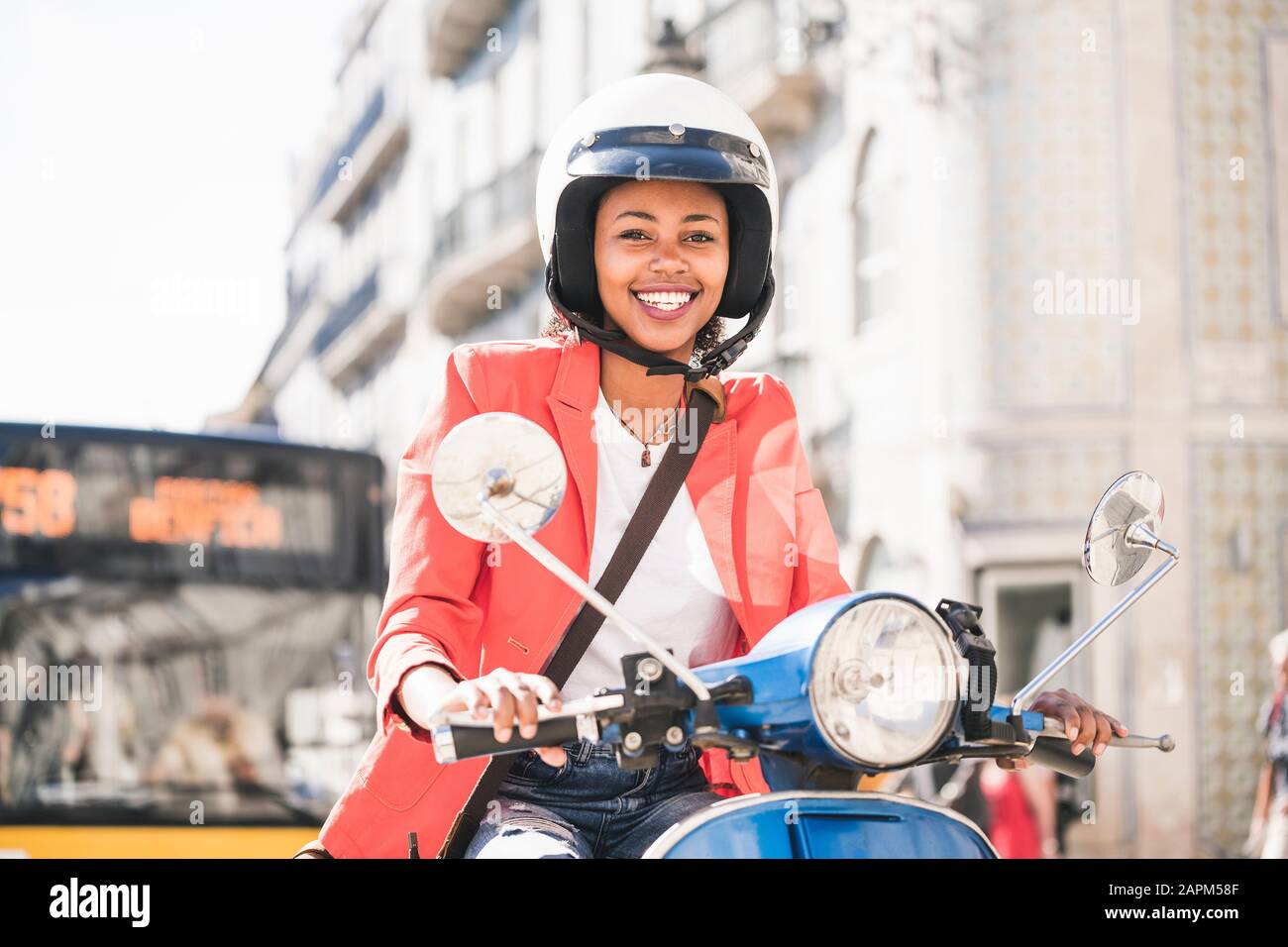 Portrait de heureuse jeune femme qui monte en scooter motorisé dans la ville, Lisbonne, Portugal Banque D'Images