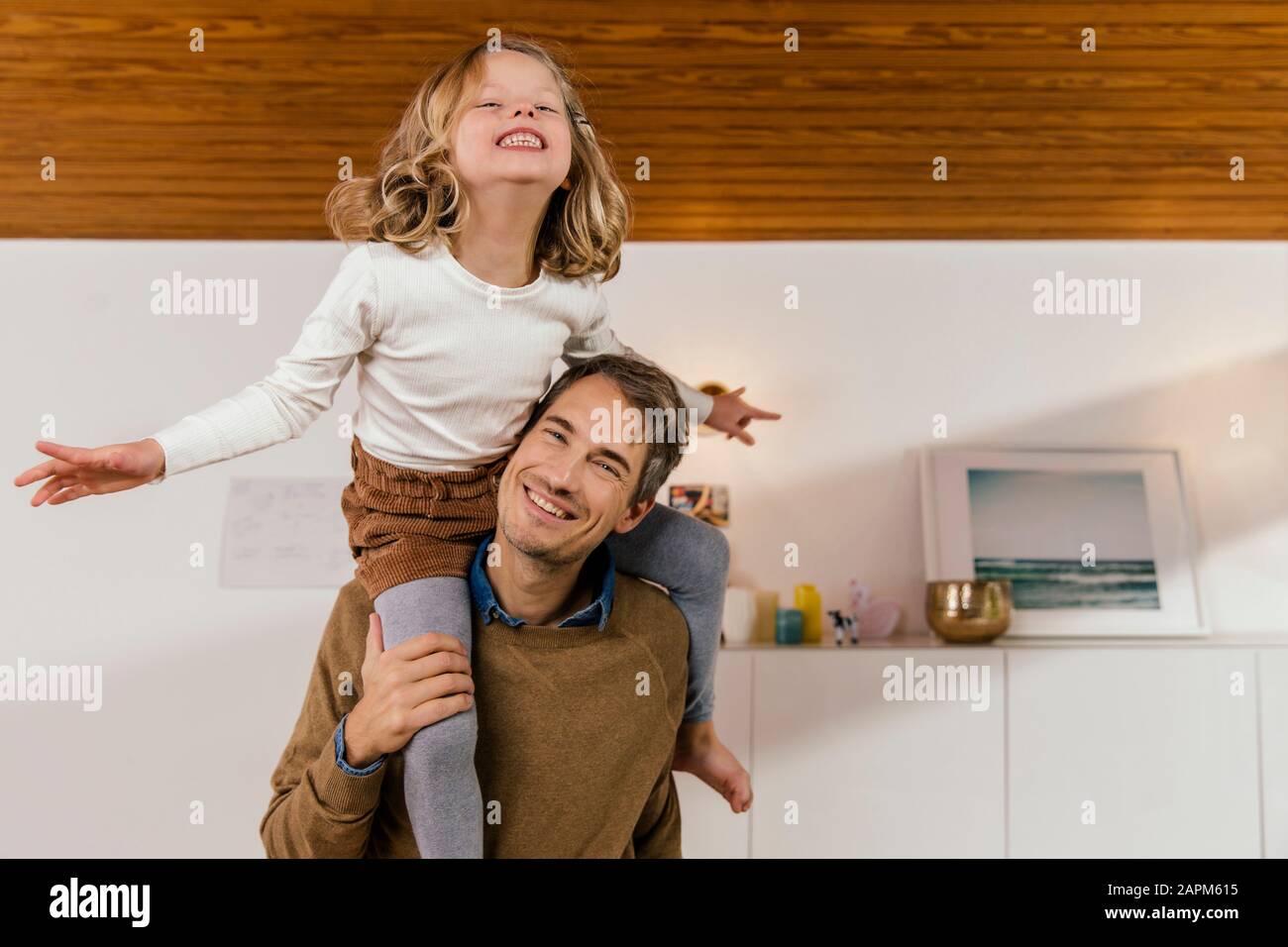 Joyeux père portant sa fille sur les épaules à la maison Banque D'Images
