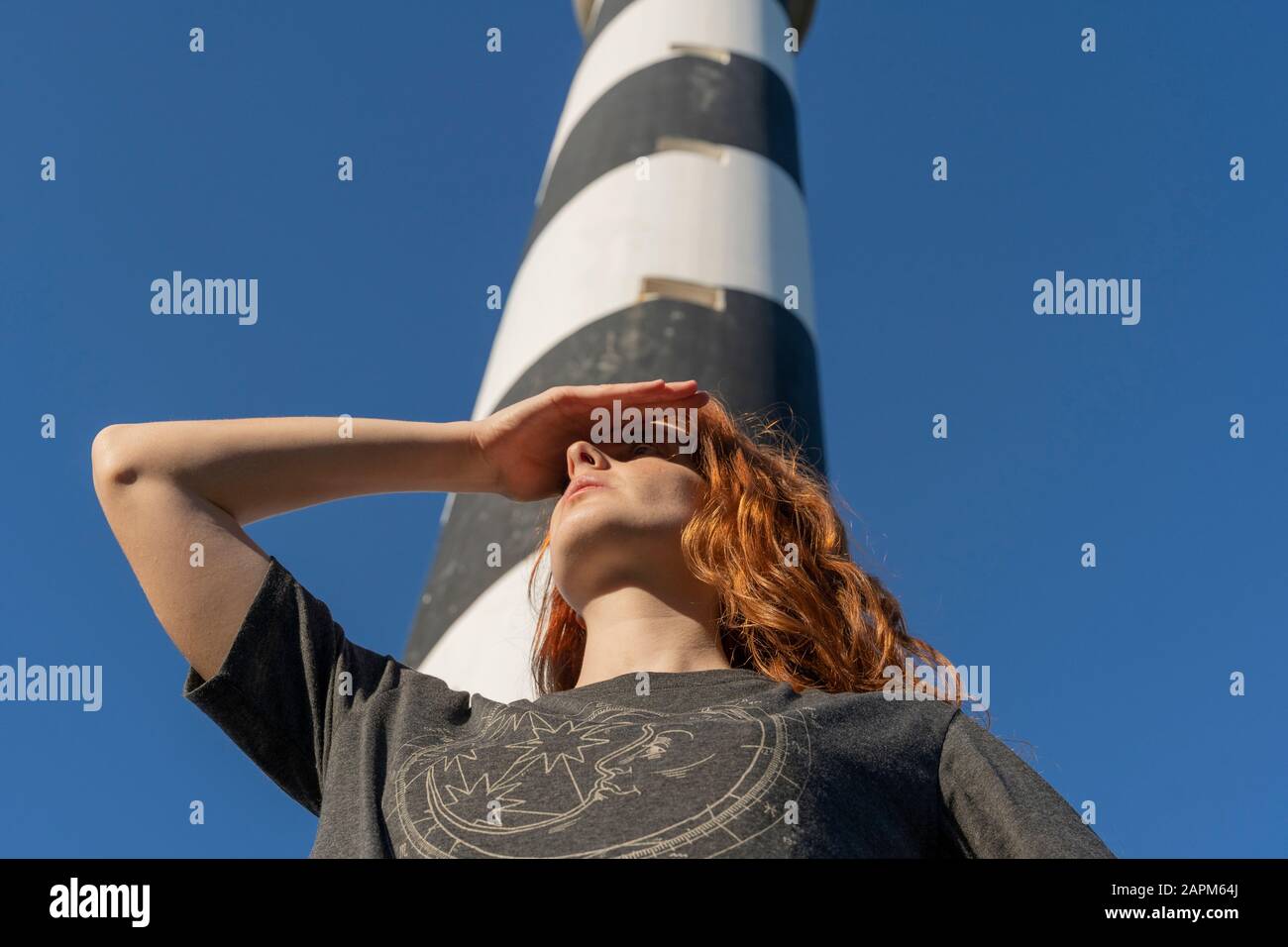 Jeune femme à tête rouge dans un phare qui regarde dehors Banque D'Images
