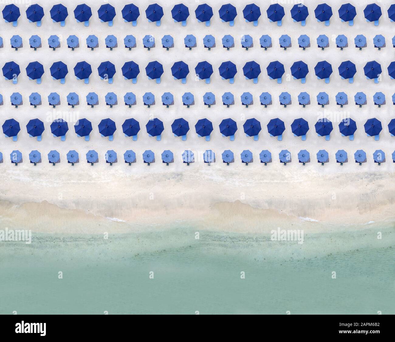 Vue aérienne sur des rangées de parasols bleus se tenant le long de la plage de sable côtière Banque D'Images