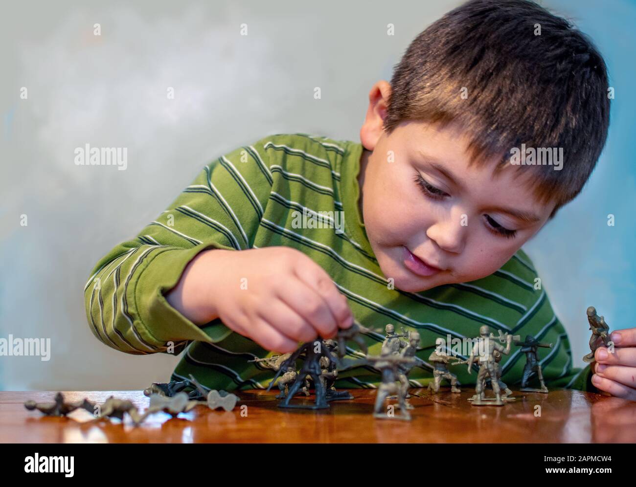 Le jeune garçon joue avec des figurines de soldat jouet Banque D'Images