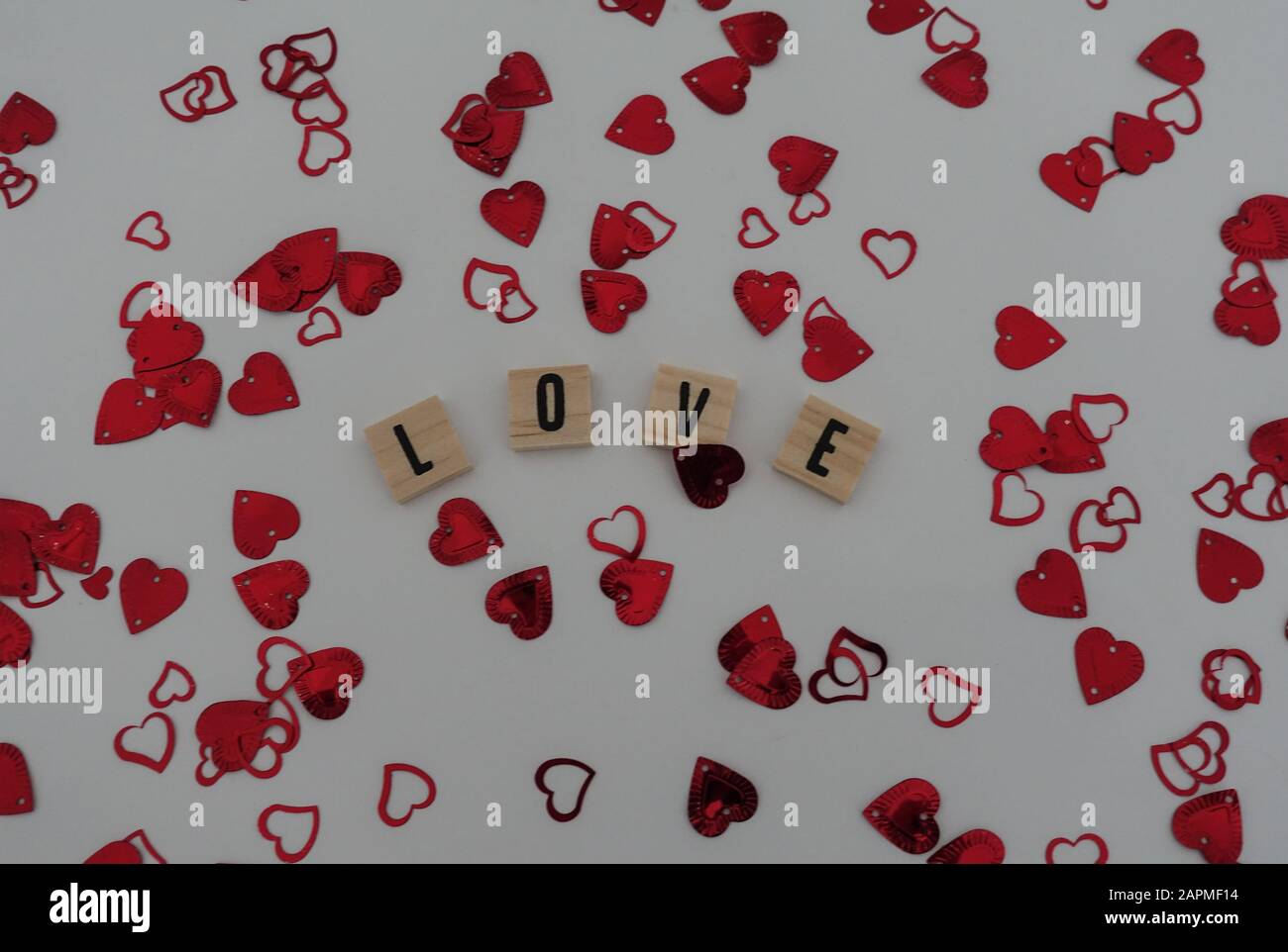 Lettres artisanales en bois qui épeler l'amour avec le cœur rouge confetti sur un fond blanc. Concept amour, romance, mariage, engagement, anniversaire et valen Banque D'Images